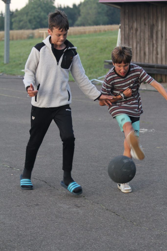 Zwei Kinder spielen Fußball auf dem Asphaltplatz